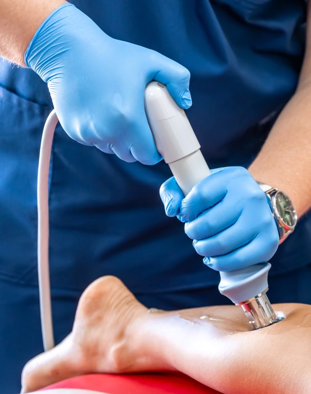 Shock wave therapy, the magnetic field, rehabilitation, physiotherapist doctor performs surgery on a patient's shin.